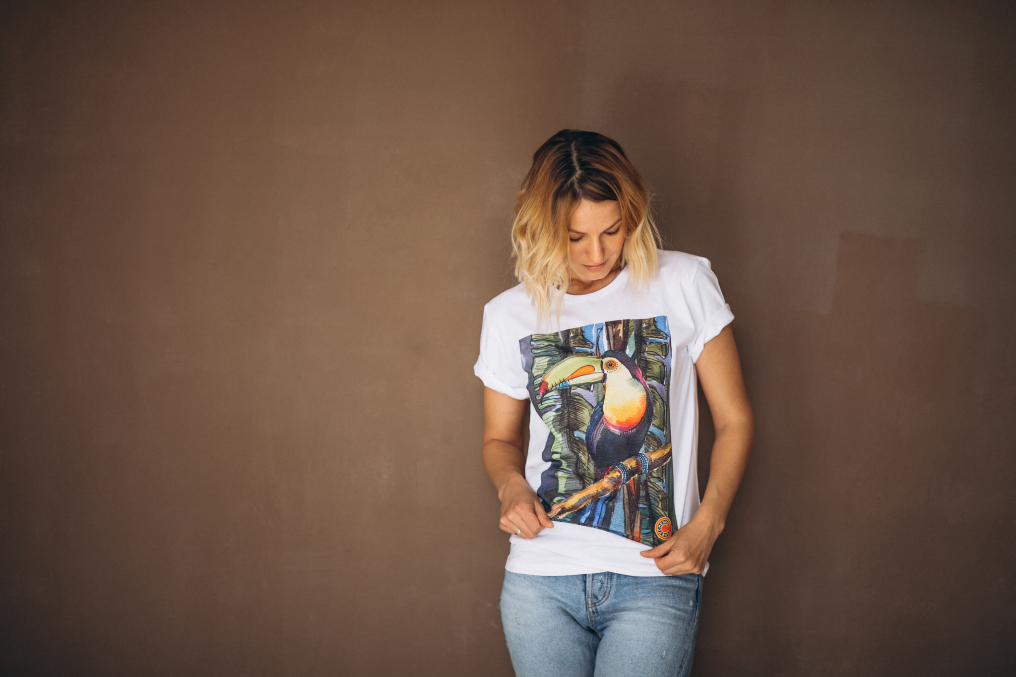 a blonde woman wearing a white shirt with a printed art of a bird.